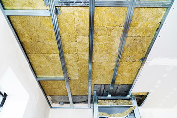 Ceiling insulation with mineral wool. Metal profile and insulation mounted on the ceiling. Evenly...