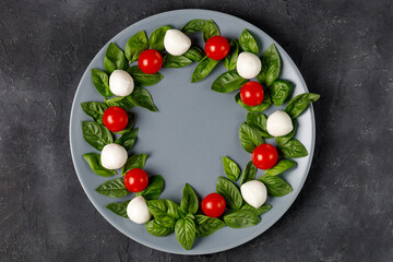 Caprese salad in the form of a Christmas wreath. Festive tomato mozzarella and basil appetizer on...