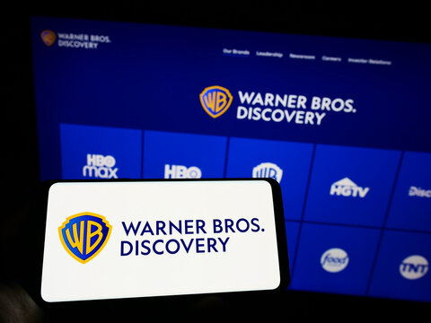 Stuttgart, Germany - 09-22-2022: Person holding mobile phone with logo of media company Warner Bros. Discovery Inc. (WBD) on screen in front of web page. Focus on phone display.