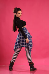 a pretty girl brunette fitness instructor, trainer, dancer go go, posing in the studio on a pink background
