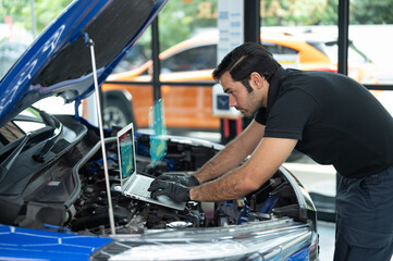 Mechanic Asian man close up using laptop computer and diagnostic software to tuning fixing...