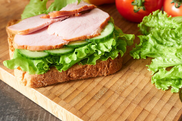 Sandwich with lettuce leaves, cucumber slices and ham slices. A delicious sandwich. 