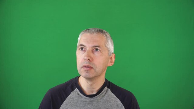 A white man about 50th old looking up and follows the movement with his gaze. A scene filmed on the background of green screen. European one adult male model with gray, short hairs.