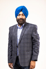 Sikh man with blue turban and grey jacket looking at camera and smiling, studio shot