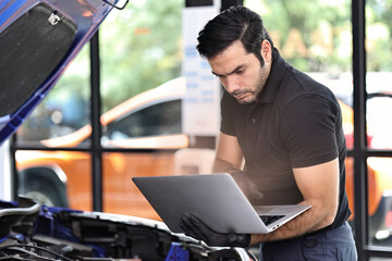 Car mechanic working with a laptop in Auto Repair Service checking car engine	