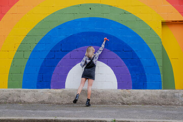 Young woman drawing on rainbow mural