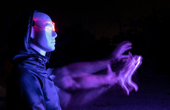 Digitally generated image of robot with blurred hand in dark