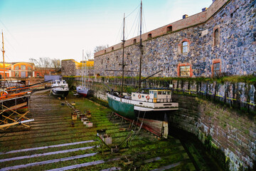 Medieval dry dock in famous Finnish Sveaborg fort on Baltic sea. Large pool without water is used for renovating and repairing wooden sailing ships. Beautiful scenery. Maritime transport. Landmark.