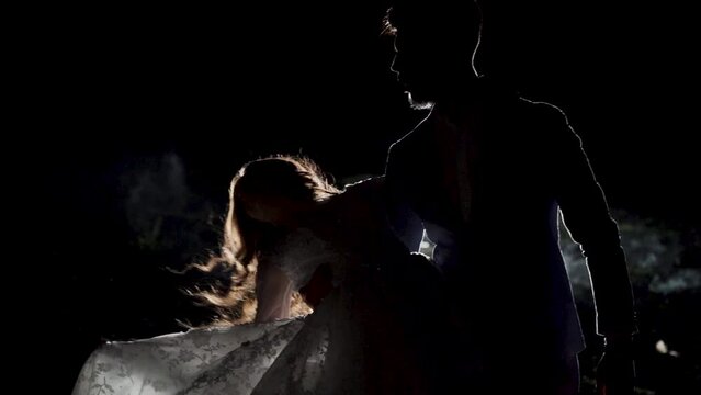 Young couple dance in a dark space with smoke. Slow motion. Silhouette