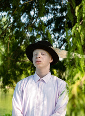Portrait of an albino man with a feathered black hat 