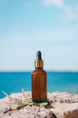 Obraz premium Glass bottle with oil or serum on the background of blue sea. Mockup, copy space