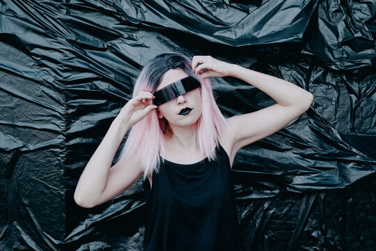 Woman wearing futuristic eyeglasses standing in front of black plastic backdrop
