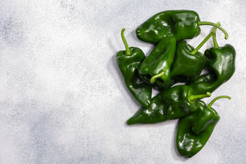 Poblano chile peppers atop grey textured backdrop, top view, copy space. Unripe ancho chilies....