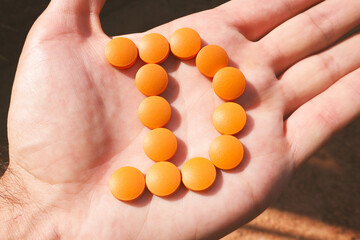 Fototapeta na wymiar Orange pills in the shape of the letter D on the male palm. Vitamin D.