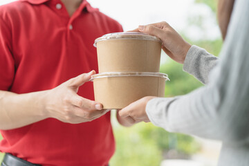 Client receiving lunch box from delivery man at home.