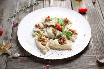 Polish pierogi, on a plate, on a wood table, top view. Traditional dumplings topped with fried...