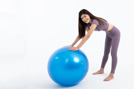 Portrait images of Asian attractive woman smile and wearing gym clothes Holding a blue exercise ball, On white background, to Exercise for health and weight loss concept.