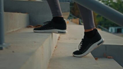 Active woman in sports sneakers climbing stairs on stadium area close up female athletic legs walking staircase cardio exercises training endurance slowly jog outdoors lifestyle activity for wellness - Powered by Adobe