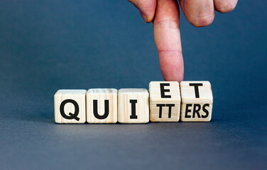 Quiet quitters symbol. Concept words Quiet quitters on wooden cubes. Businessman hand. Beautiful grey table grey background. Business quiet quitters concept. Copy space.