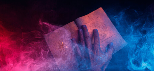A scary hand over magic book on dark background. Mysterious composition. Fortune teller, mind...