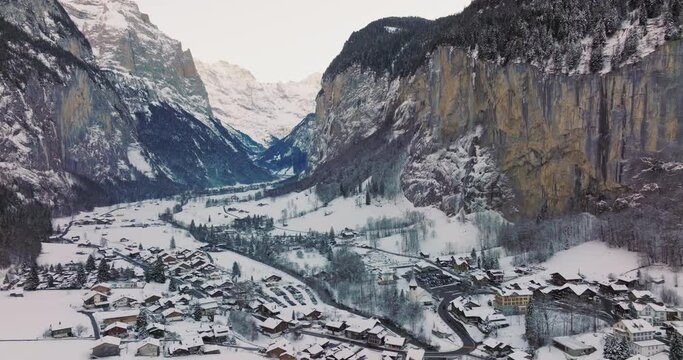 Panorama aerial Drone shot of Cottages chalets in Lauterbrunnen village at snowy winter. Traditional Walser mountain village in the canton of Bern in Switzerland. Popular tourist spots in Interlaken.