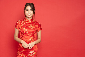 Young Asian woman wearing red traditional cheongsam qipao dress isolated on red background, Happy Chinese New Year concept