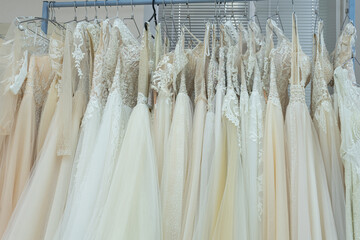 White and cream wedding dresses on a hanger in a bridal boutique. Close up