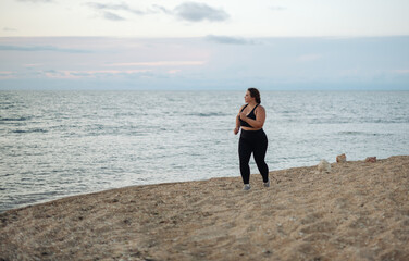 Overweight beautiful woman running at the seashore. Copy space. The concept of sport and activity. Body positive