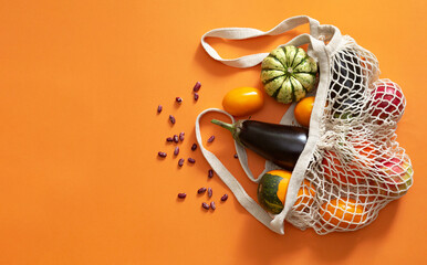 Eco bag with fresh organic vegetables and fruits on orange  background. Autumn harvest. Concept of ...