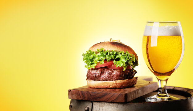 Draft beer glass and hamburger on wooden barrel