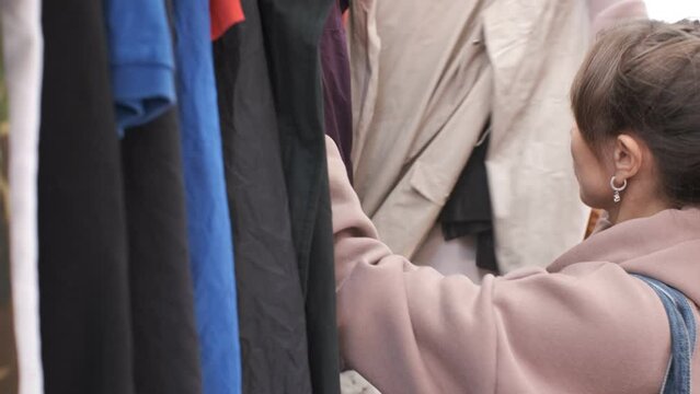 Girl chooses clothes in a thrift store