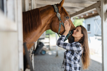 Young woman in a stable with her horse
