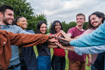 Group of young people joining hands to join forces and work as a team