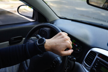 Fototapeta na wymiar Close-up shot of a man's hand holding a car's steering wheel.