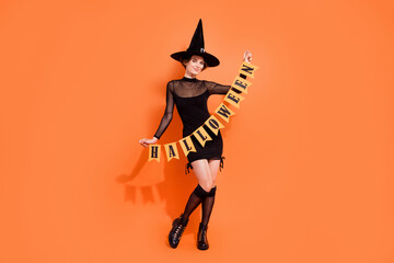 Full size photo of pretty young woman hold party decoration dressed trendy black halloween witch...