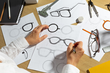 The designer draws a sketch of eyeglasses on paper. Creating glasses.