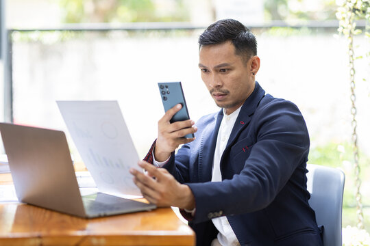 Take picture, Asian Businessman sitting at workplace desk and Taking Photograph Of Document In Office