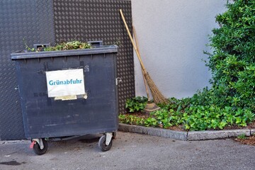 Plastic container full of garden waste. It has an inscription in German language saying Green...