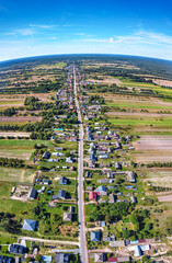 Aerial, panoramic view on a village by long straight road.
