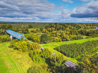 Aerial view of a blue bridge over a lazy river in green scenery