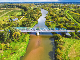 Aerial view of a blue bridge over a lazy river in green scenery