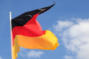 German flag with the colors of germany waving and the blue sky