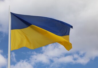 Blue and Yellow Flag of the Ukrainian nation waving in the sky with white clouds