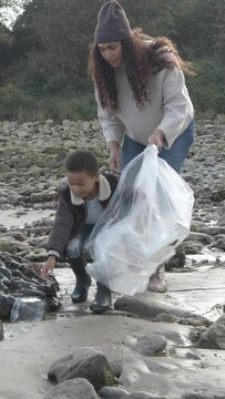 Mother and child cleaning beach, environmental issues, education, volunteering