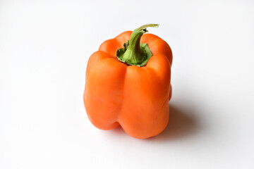 Orange large pepper fruit on a white background. Beautiful ripe pepper close-up.