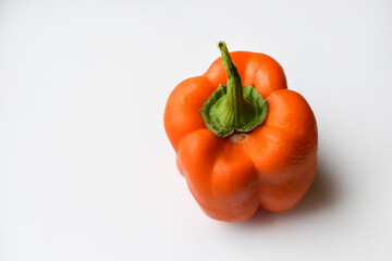 Orange large pepper fruit on a white background. Beautiful ripe pepper close-up.