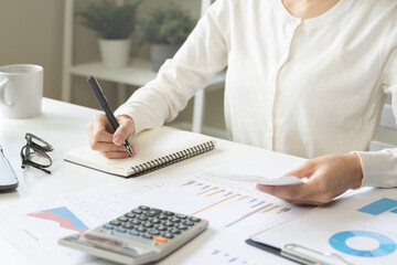 Account finance, analysis asian business woman hand use pen for calculate budget, cost and income of company from on bills, reports paperwork, plan spend money expenses, working on desk at home.