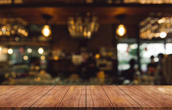 	
Empty wooden table top with lights bokeh on blur restaurant background.