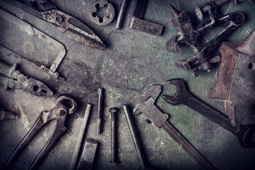 grungy old metalwork tools on stained table background (processing cross-process)