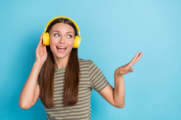 Portrait photo of young carefree woman wear striped khaki t-shirt dancing celebrate listen music headphones look empty space isolated on blue color background